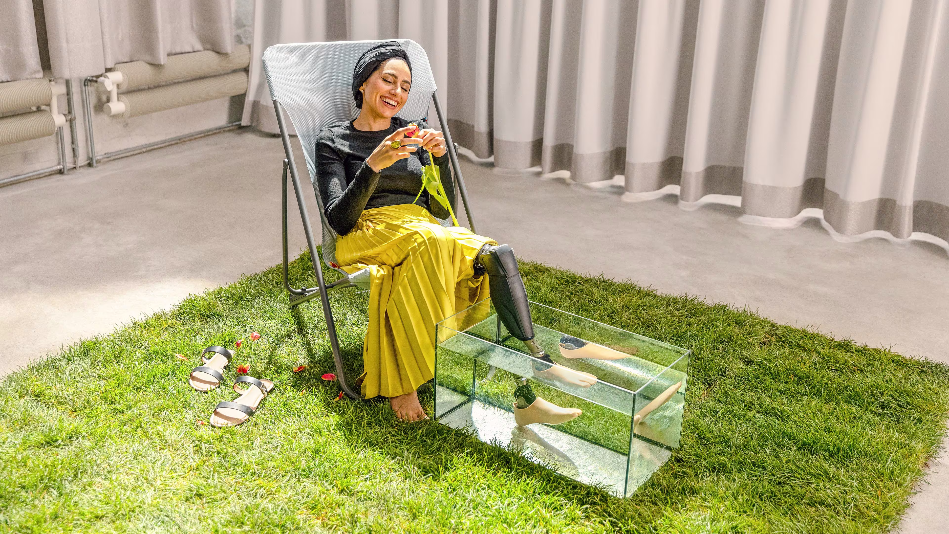 Zainab sitting on a chair resting her Genium X3 and Taleo Adjust in a glass container full of water. 