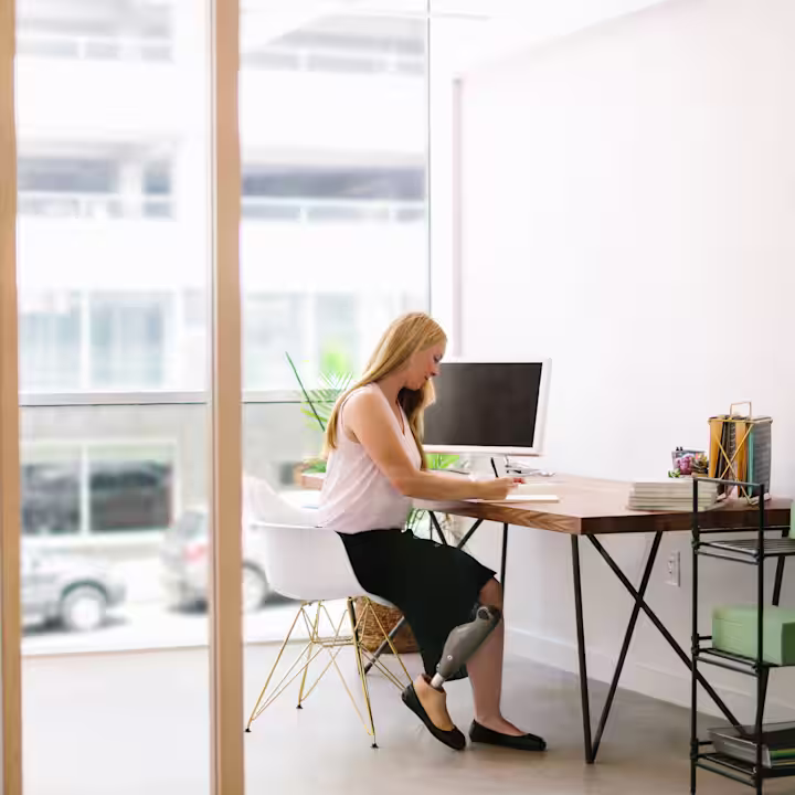 An amputee writes on a notebook in their office