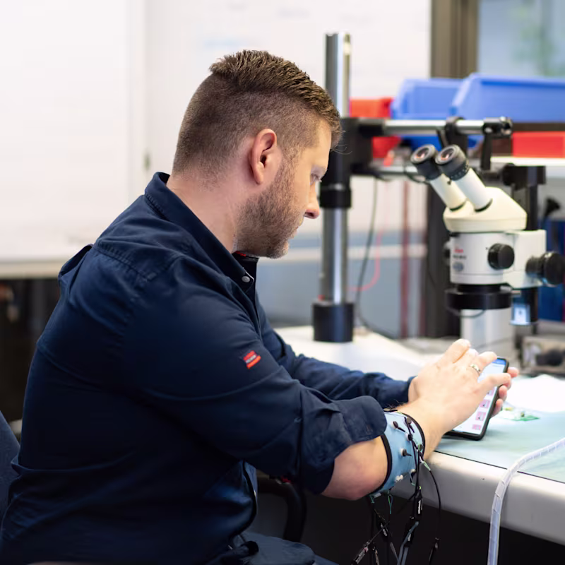 Mitarbeiter aus dem R&D Bereich prüft Funktionalität einer Armprothese mithilfe einer App.