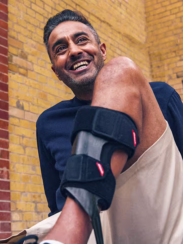 Un utente sorridente di Ottobock WalkOn seduto davanti a un muro di mattoni.