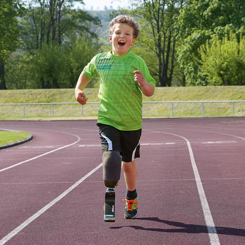 Un giovane atleta con una protesi alla gamba corre su una pista all'aperto