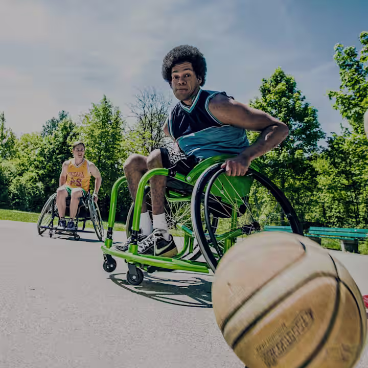Experience the joy of inclusive sports with two athletes playing wheelchair basketball using Ottobock Multisport and Pointer wheelchairs. Captured on a sunny day, this photo celebrates the spirit of fun and accessibility in outdoor activities.