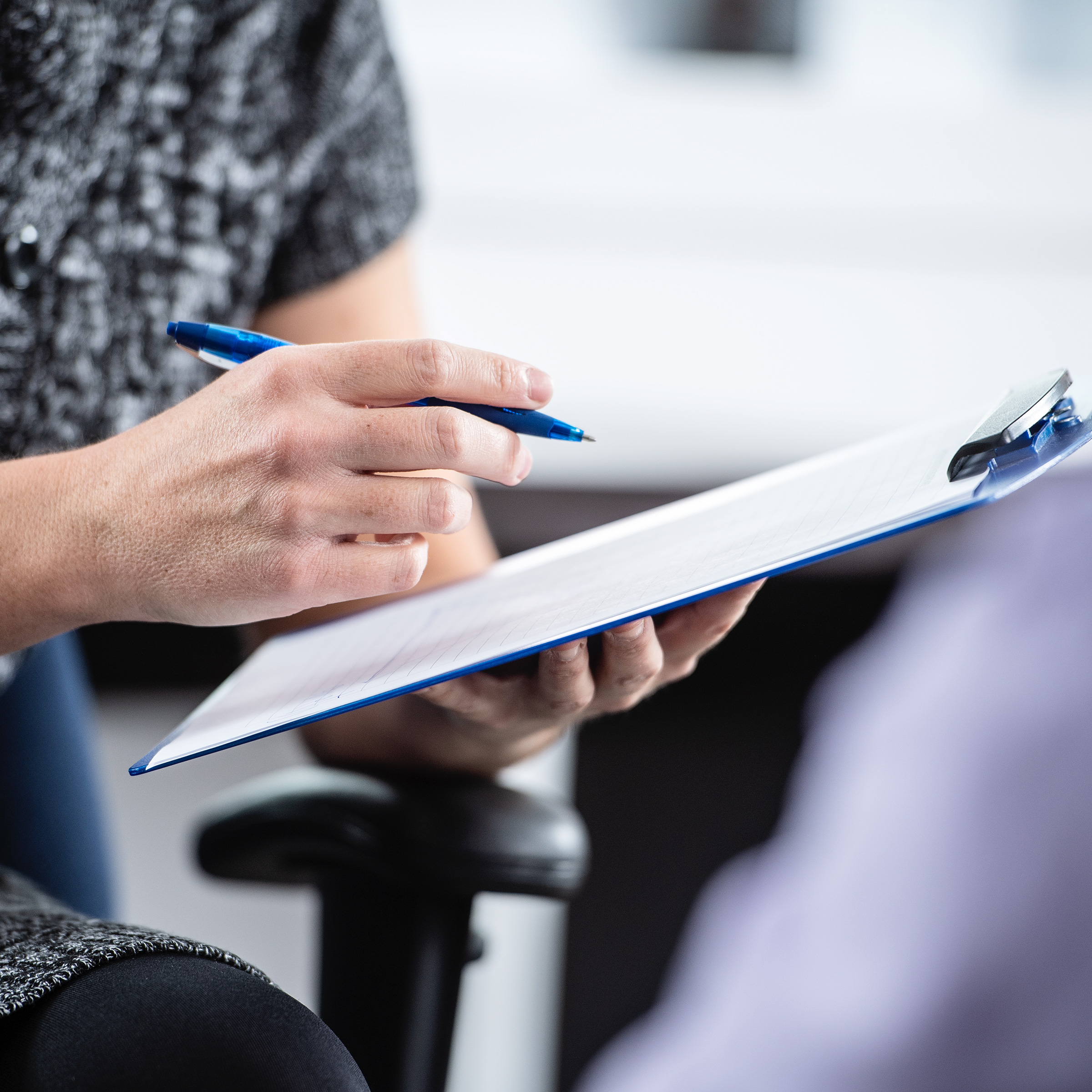 Close-up of a woman’s hands making notes in her notebook.