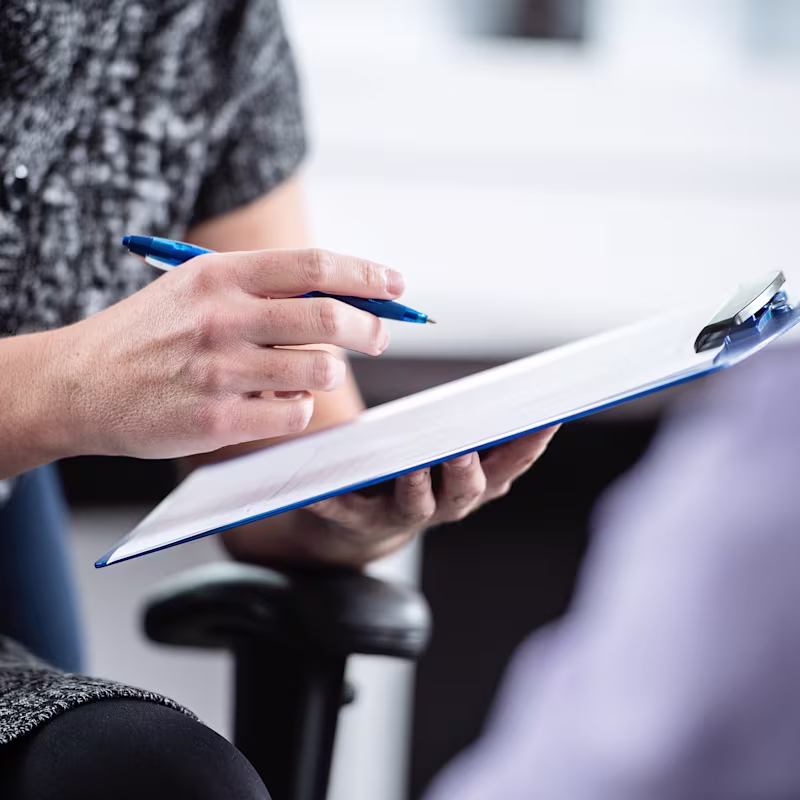 Close-up of a woman’s hands making notes in her notebook.
