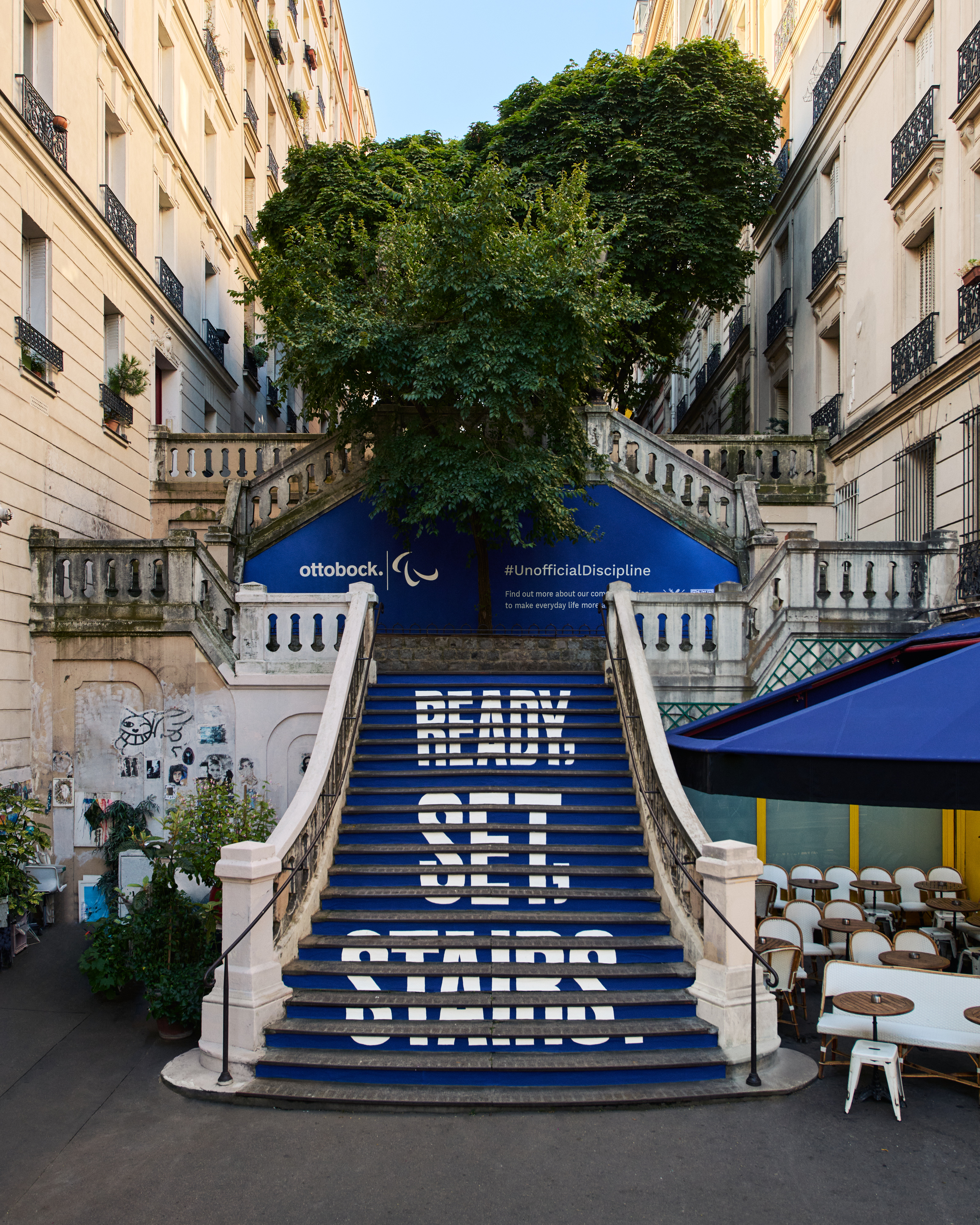 Geschilderde blauwe trap met lichtblauwe tekst in een stedelijke omgeving; er staat: ready, set, stairs (klaar, ingesteld, trap).