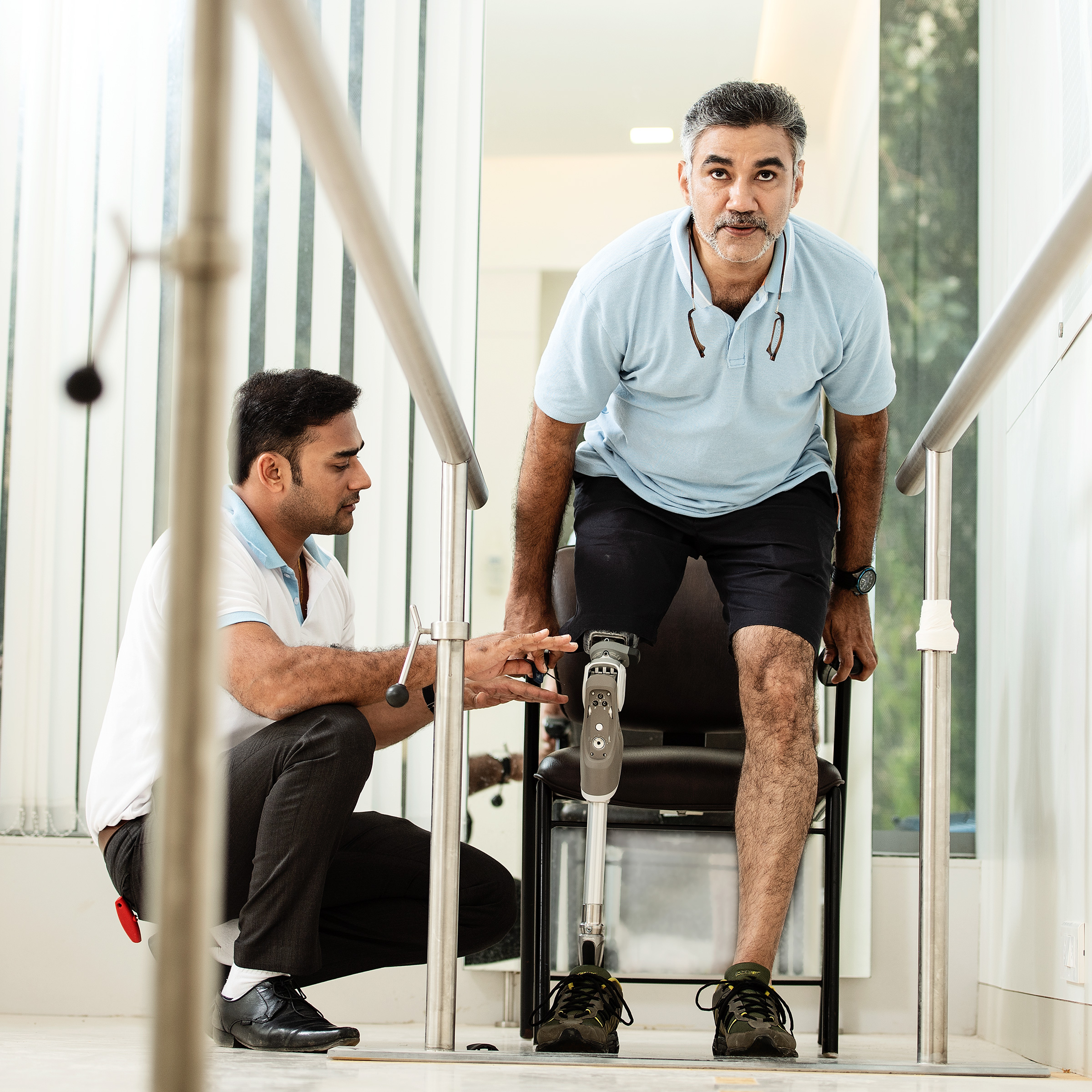 Ottobock prosthetic leg user practicing sitting down with guidance from an O&P specialist.