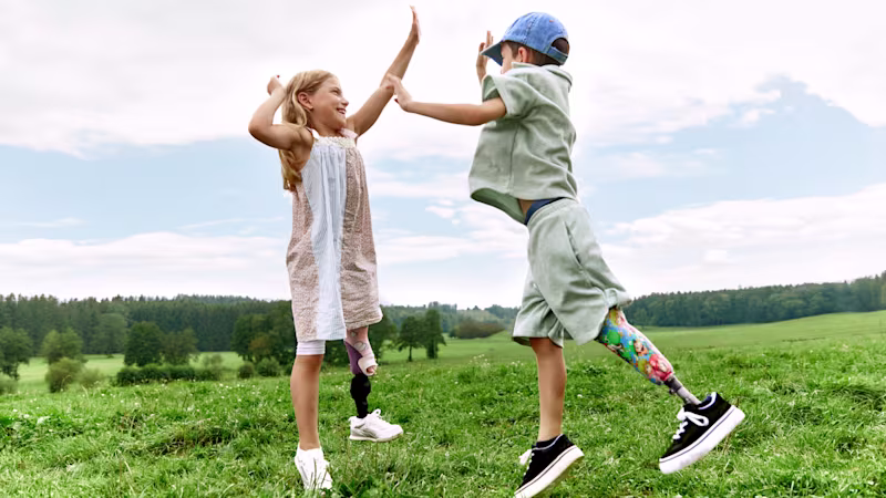 Auf dem Bild sieht man zwei Kinder, einen Jungen und ein Mädchen. Beide springen hoch und klatschen sich in der Luft zu. Das Mädchen trägt das Movido Kniegelenk mit dem Maverick junior Prothesenfuß und der Junge trägt den Maverick junior Prothesenfuß.