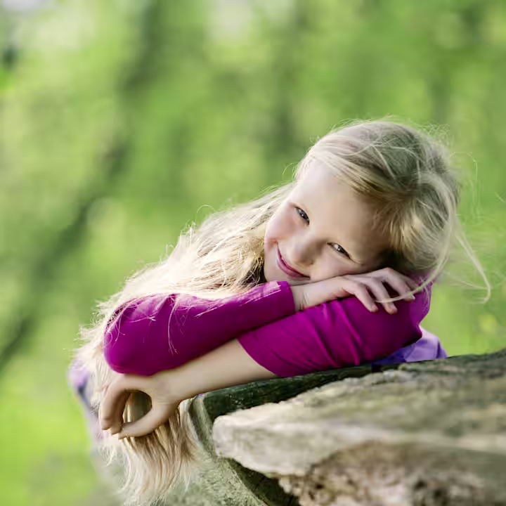 Girl with an Ottobock prosthetic hand smiling at the camera.