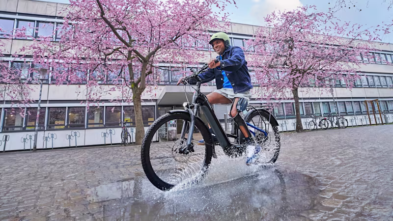 A smiling man cycling, wearing a C-Brace.