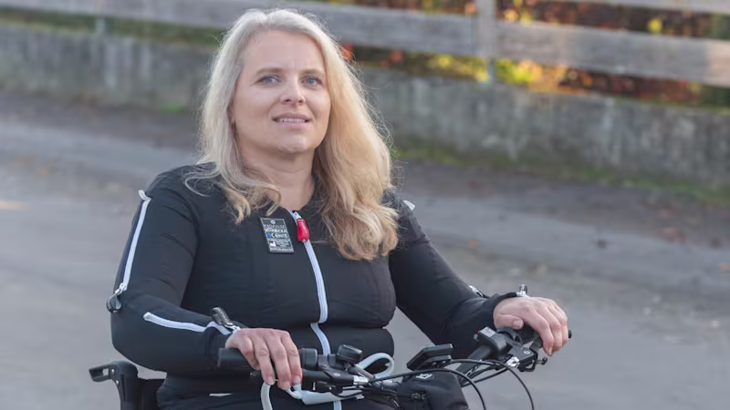 Kerstin siede su una carrozzina Avantgarde DV e utilizza un Klaxon Klick Race come dispositivo di trazione. Indossa la neurotuta Exopulse.