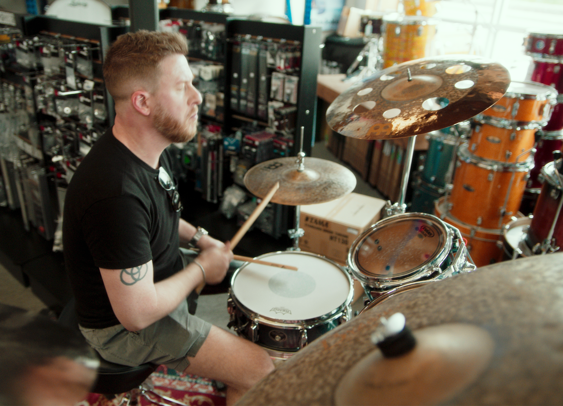 Man with lower limb loss Billy Brimblecom plays drums at a music shop.