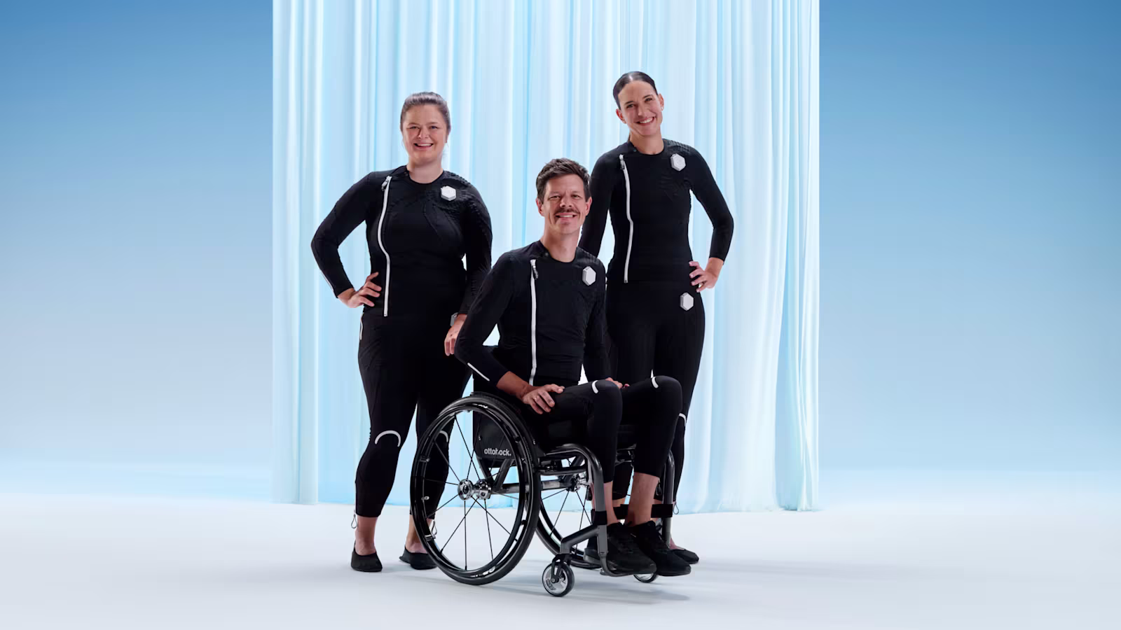 Ottobock users Lena, Ricky and Jacqueline stand and sit as a group in their exopulse suits.