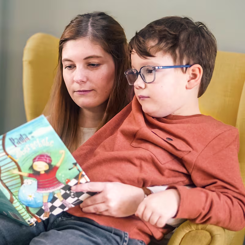 Zerebralparese Patient liest zusammen mit seiner Mutter