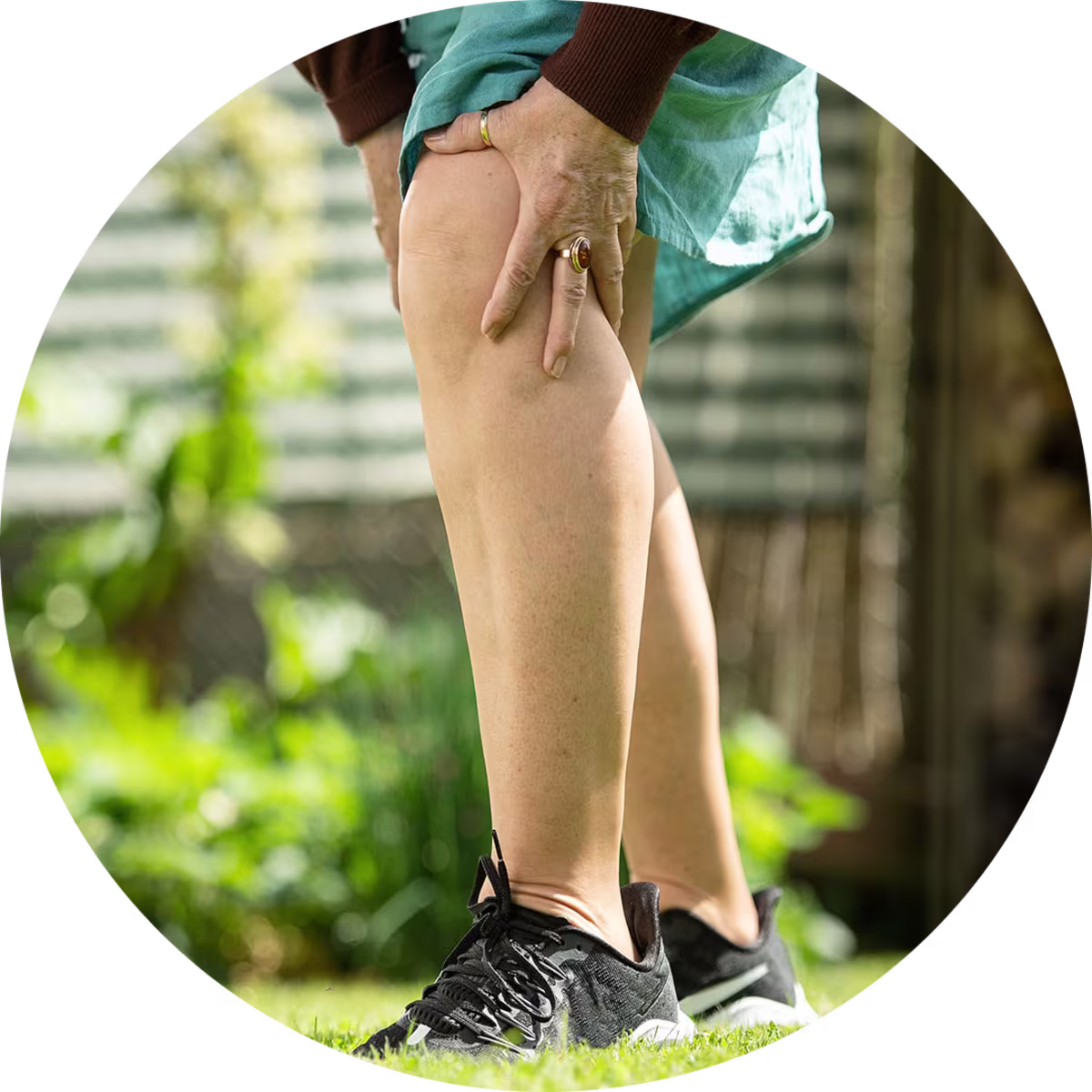 Bildausschnitt von dem Unterkörper einer Frau, die sich vor Schmerzen das Knie hält.