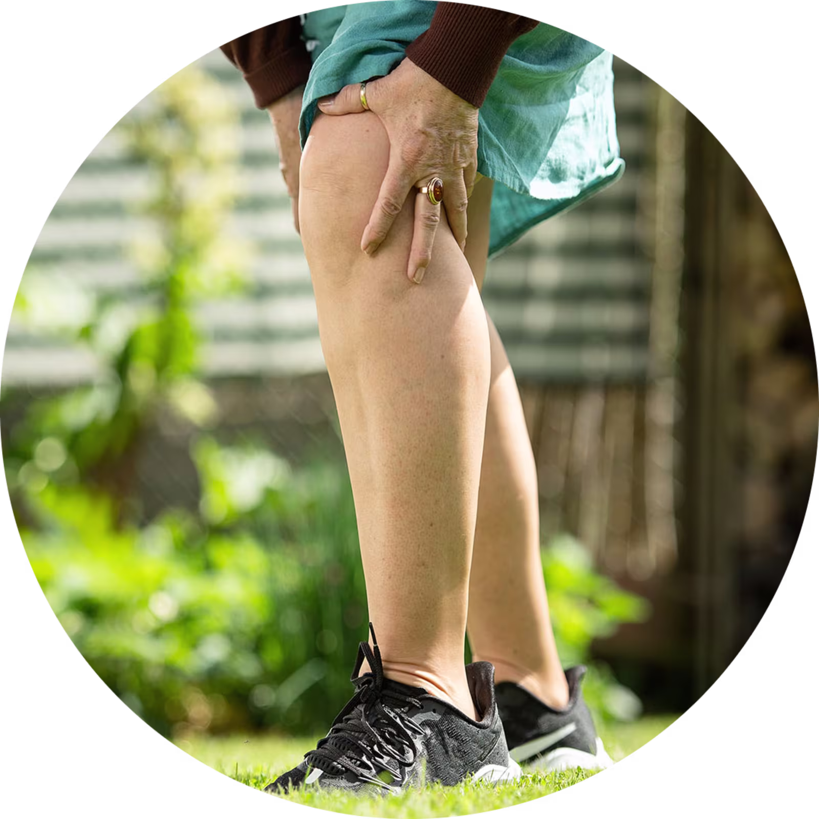 Bildausschnitt von dem Unterkörper einer Frau, die sich vor Schmerzen das Knie hält.