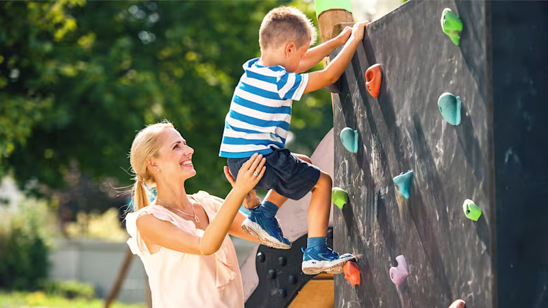Eine Armprothesenträgerin spielt mit Ihrem Kind auf einem Spielplatz. Sie trägt die MyoHand VariPlus Speed von Ottobock.
