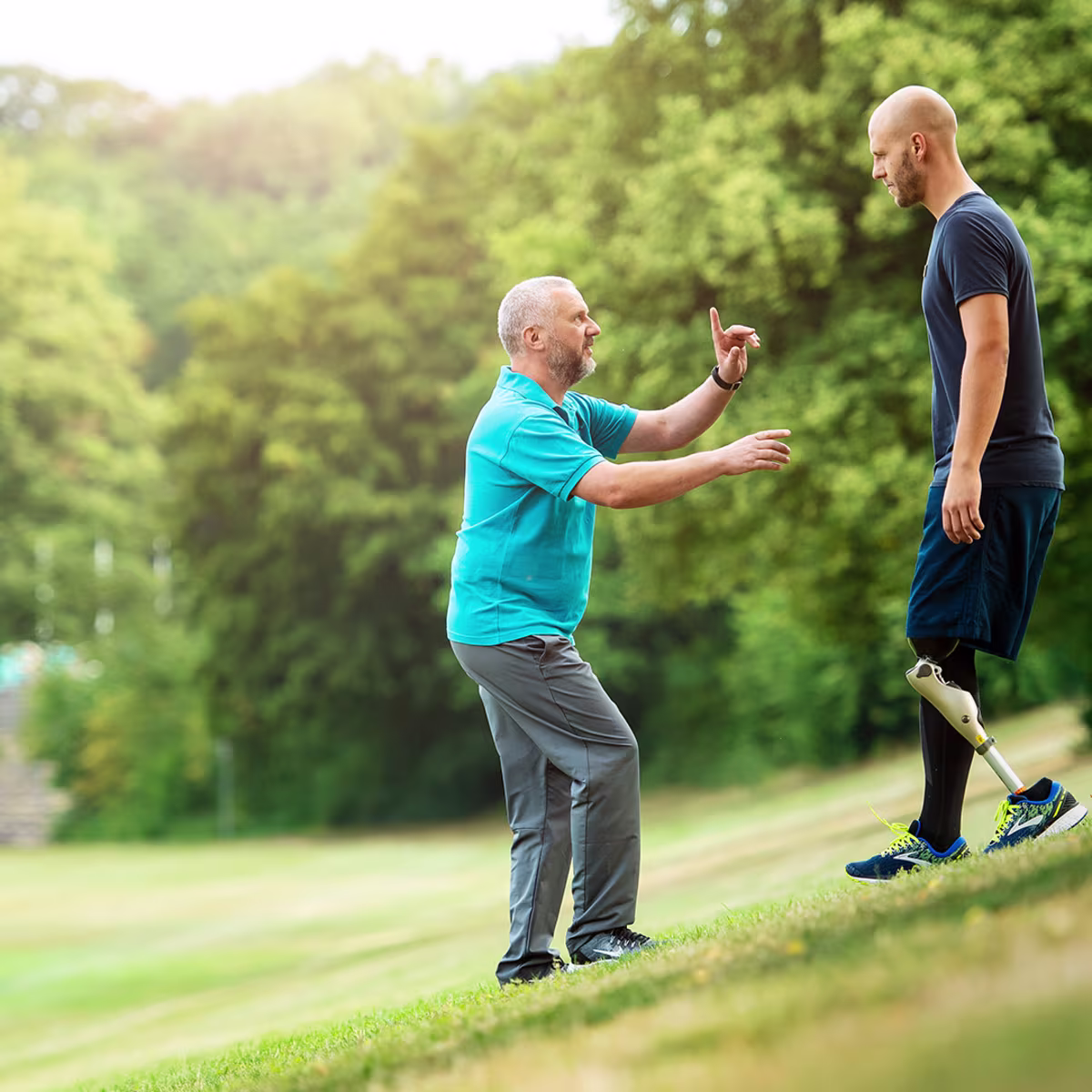 Ein Prothesenträger und sein Therapeut laufen gemeinsam einen Hügel hinunter, der Amputierte trägt dabei das mechatronische Prothesenkniegelenk Kenevo von Ottobock.