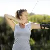 An athlete with an arm brace draws an arrow with a bow for an archer competition