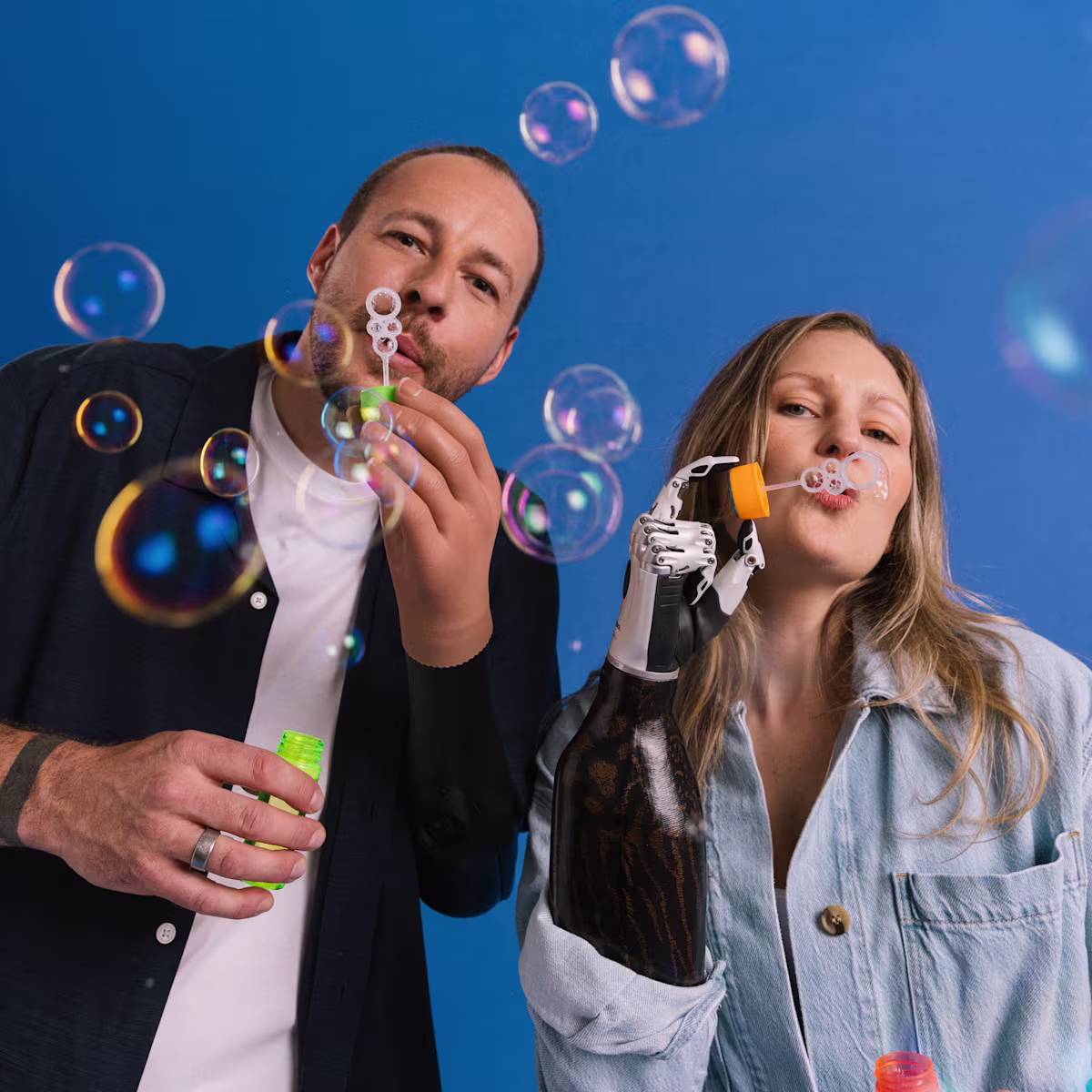Two prosthetic hand users with the bebionic and VariPlus Speed blowing bubbles.