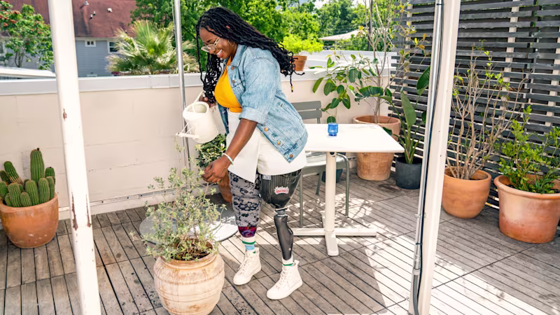 A C-Leg 4 user watering a potted plant using a watering can.