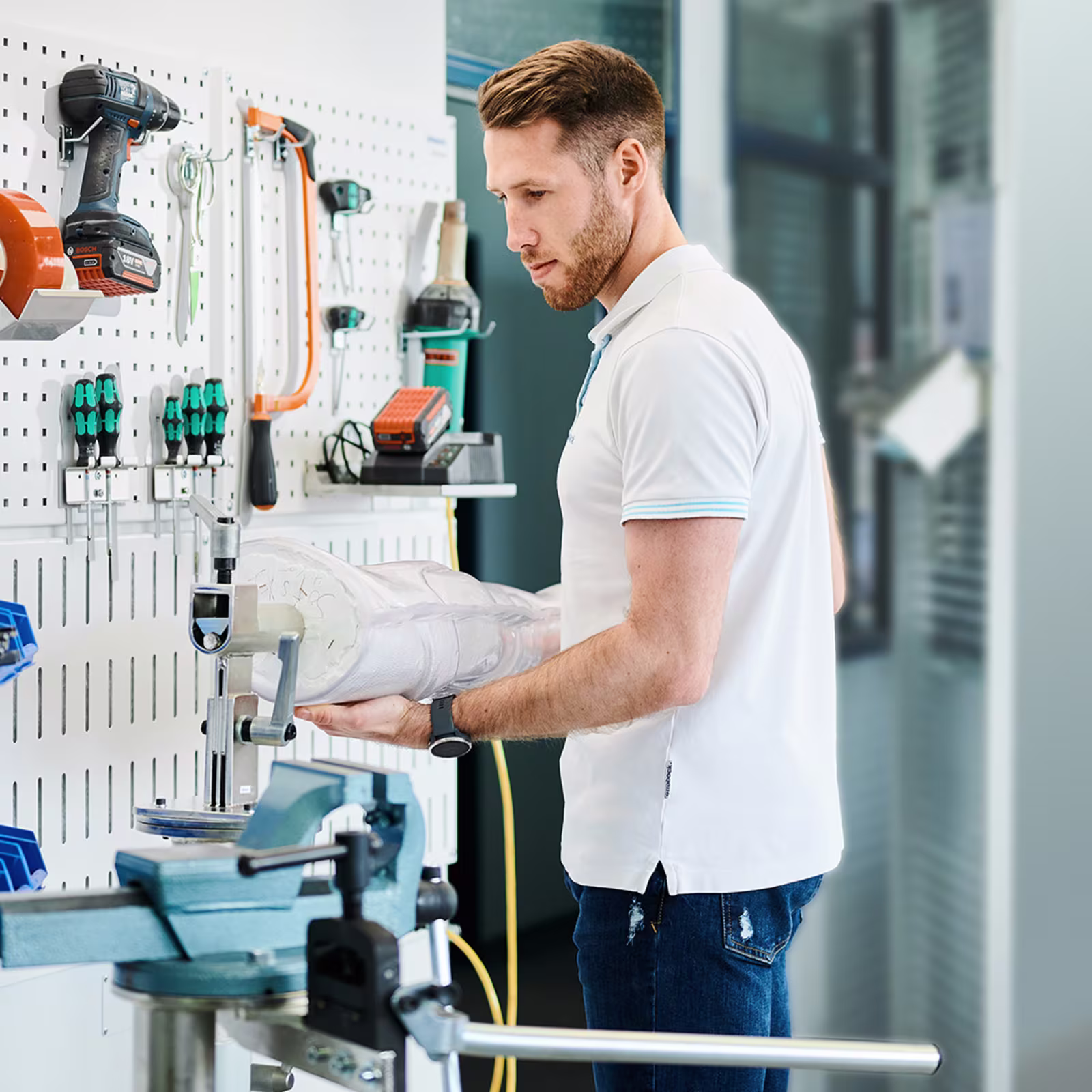Orthopädietechniker hält ein Gipsmodell in einer O&P-Werkstatt vor einem Arbeitsplatz.