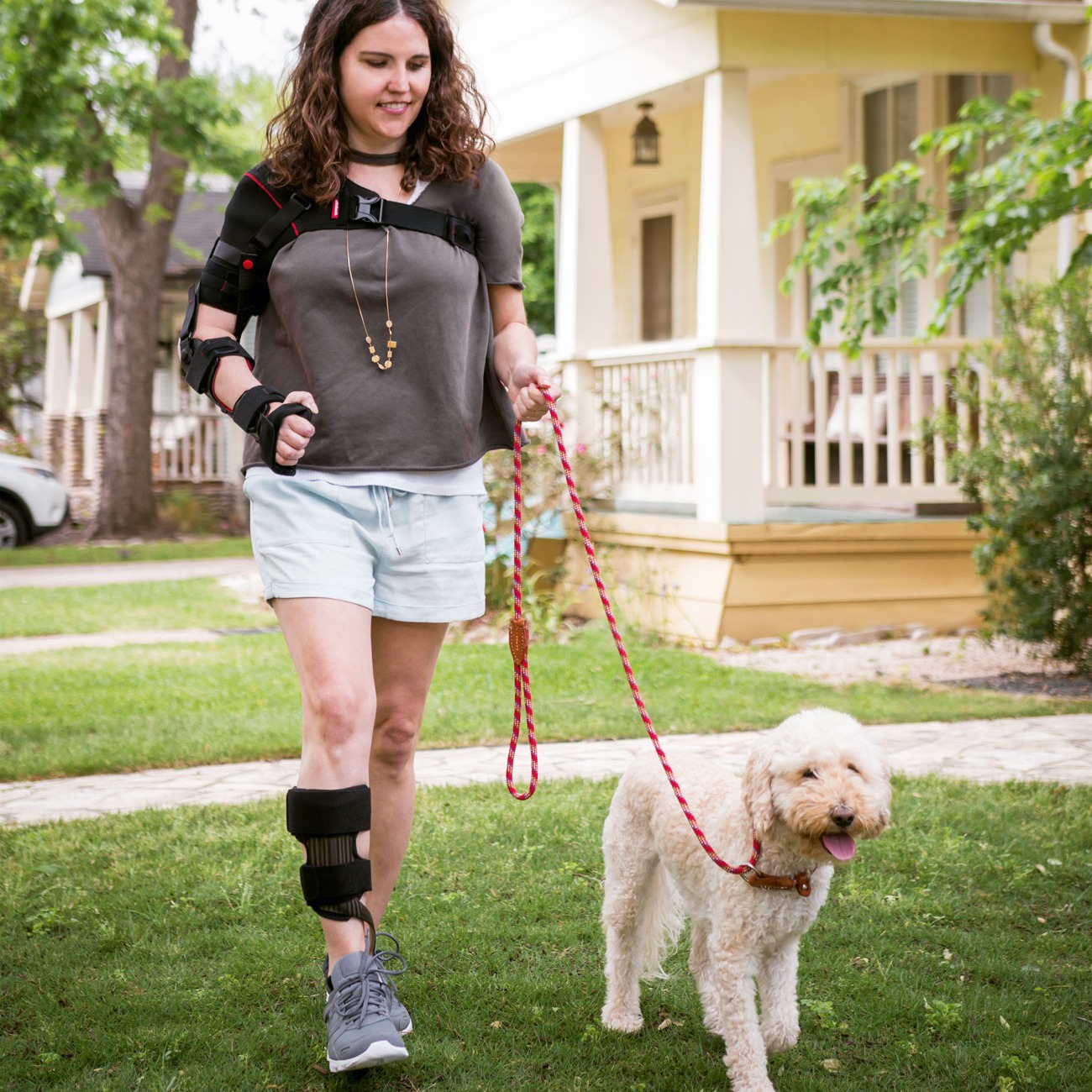A woman walking her dog while wearing her arm brace