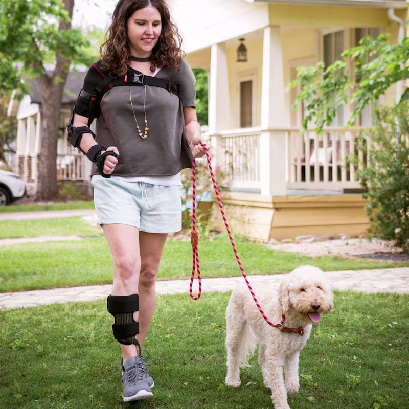 A woman walking her dog while wearing her arm brace