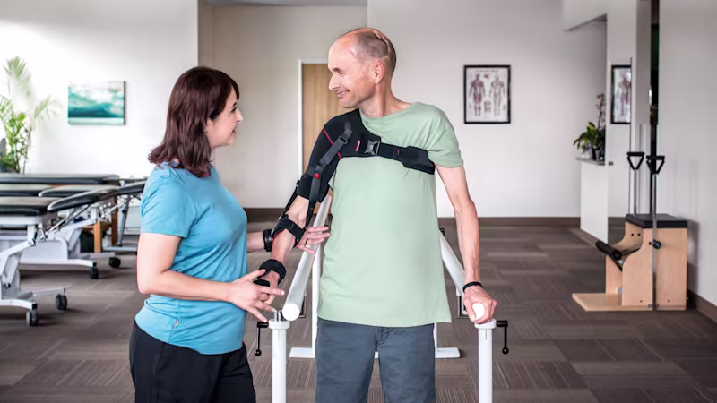 A man wearing an arm brace accompanied by a Certified Prosthetist Orthotist (CPO) in a clinic