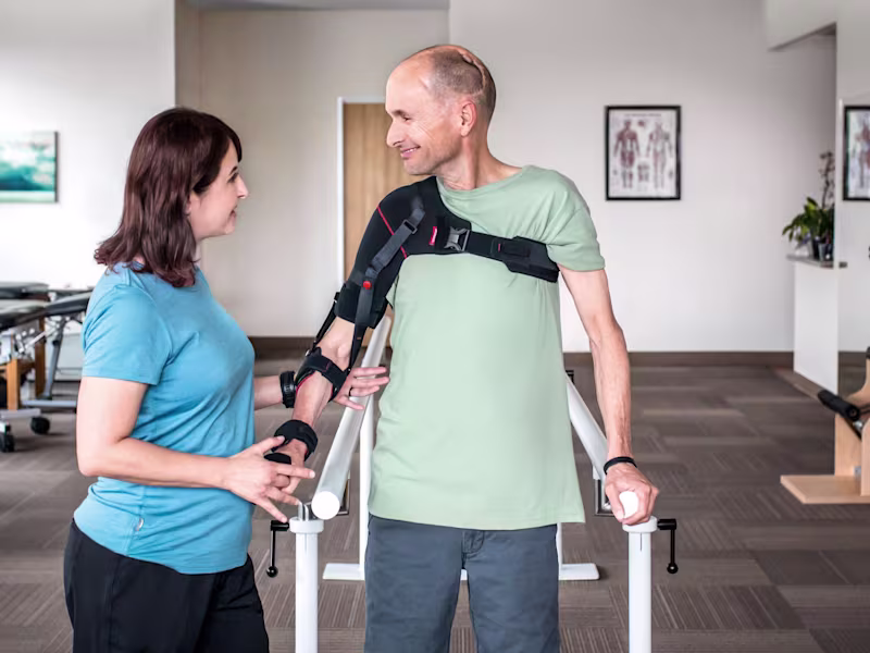 A man wearing an arm brace accompanied by a Certified Prosthetist Orthotist (CPO) in a clinic