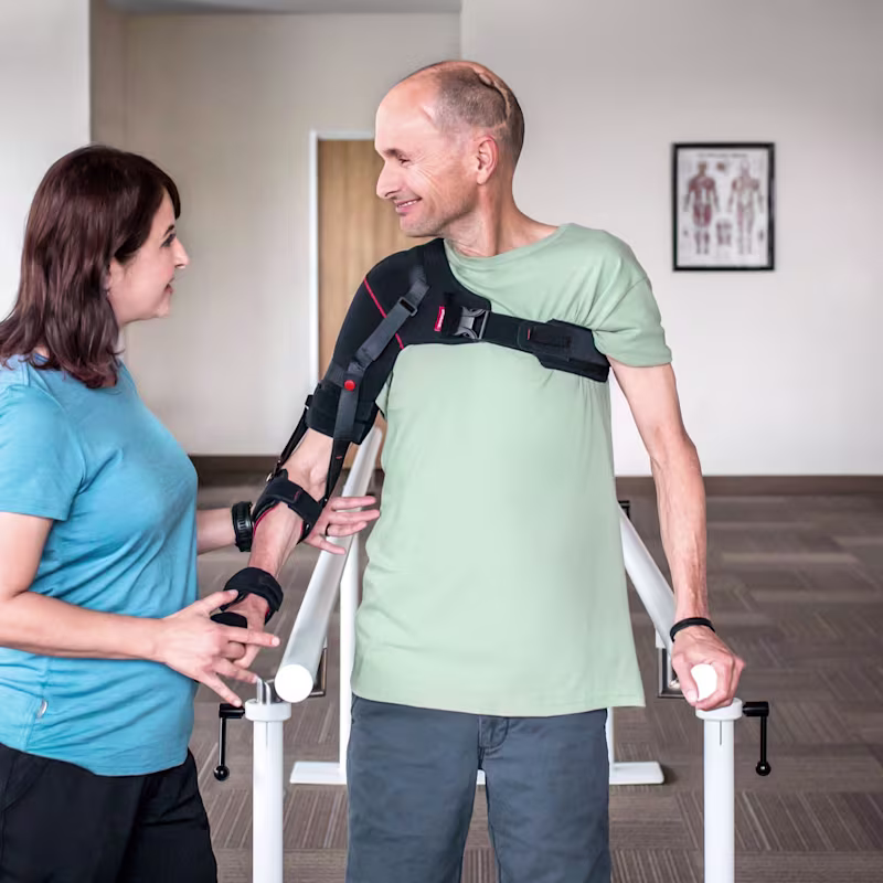 A man wearing an arm brace accompanied by a Certified Prosthetist Orthotist (CPO) in a clinic