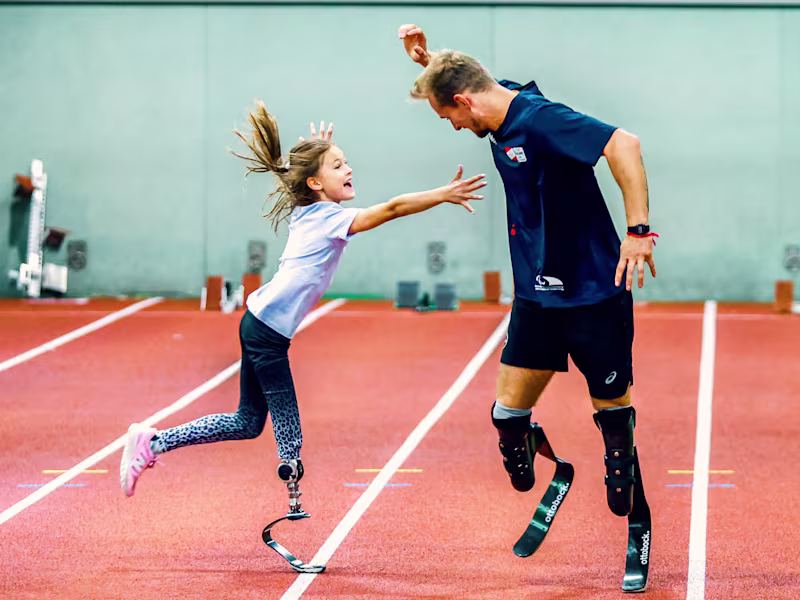 Ein Mädchen mit Prothese spielt fangen mit Johannes Floors, einem Parasport-Leichtathleten.