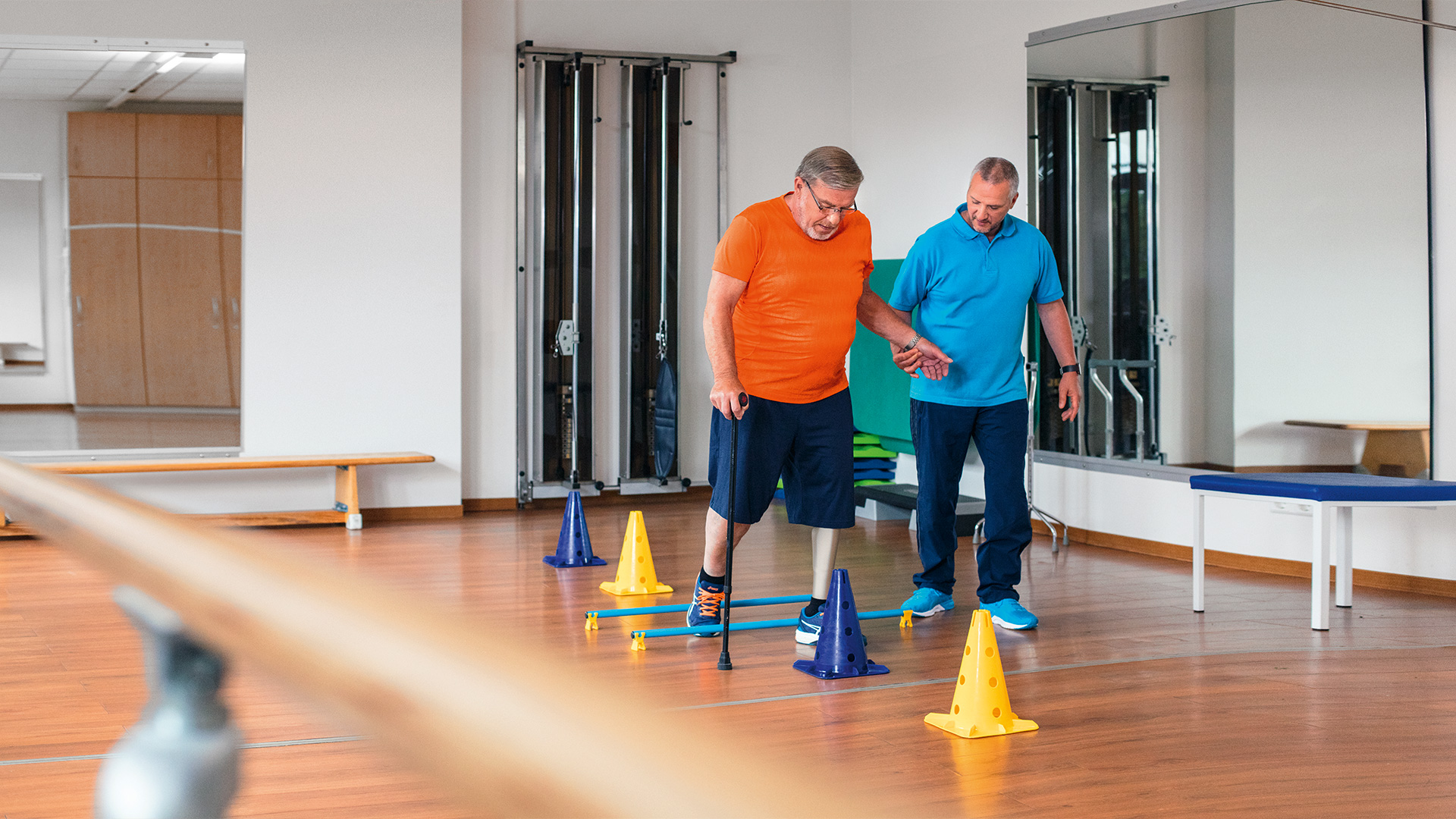 An amputee is accompanied by a physical therapist as they trial a prosthetic foot in a rehabilitation center