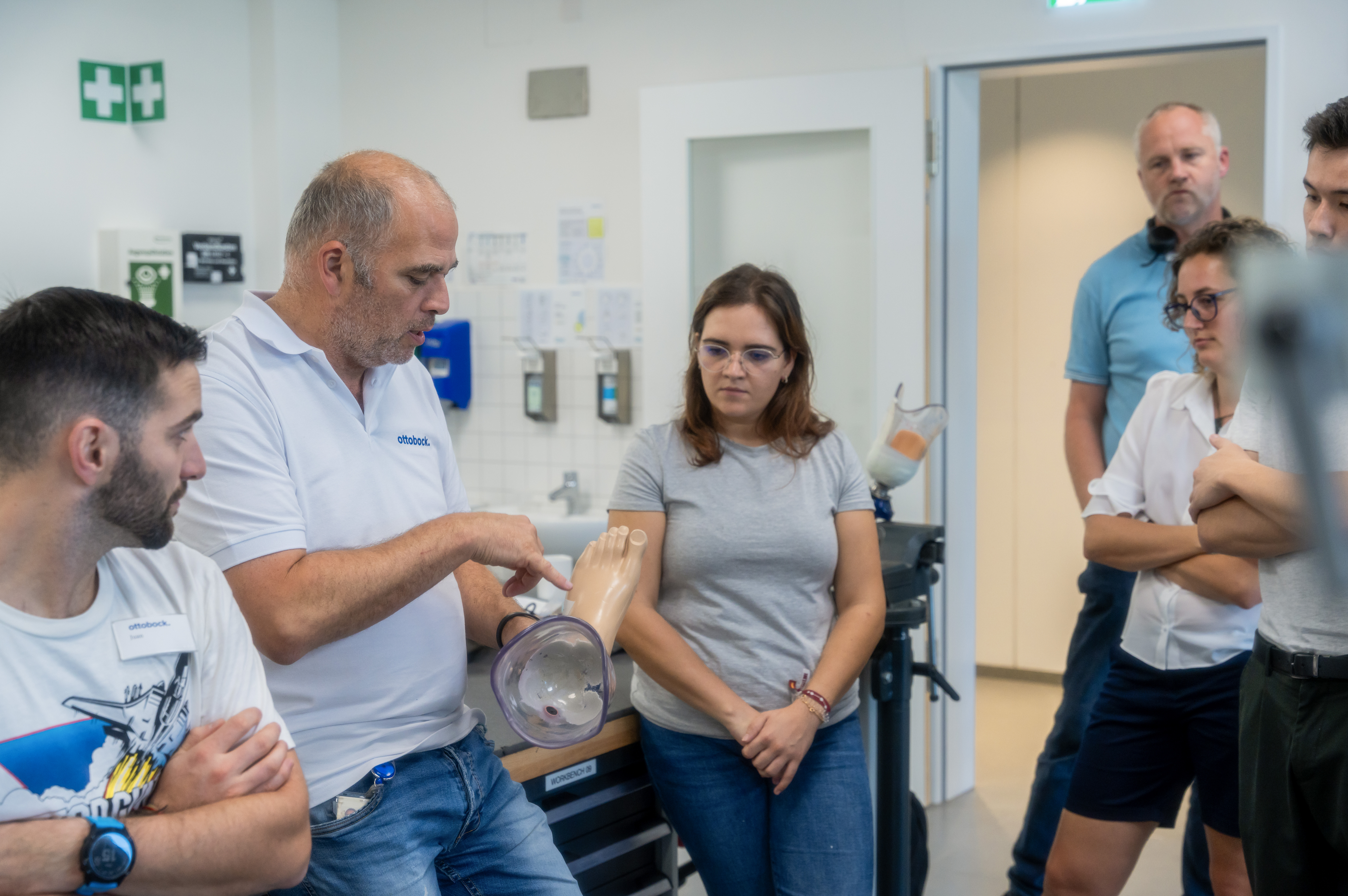 Ein Ottobock Mitarbeiter hält eine Fußprothese in der Hand und zeigt diese den umstehenden Seminarteilnehmern.