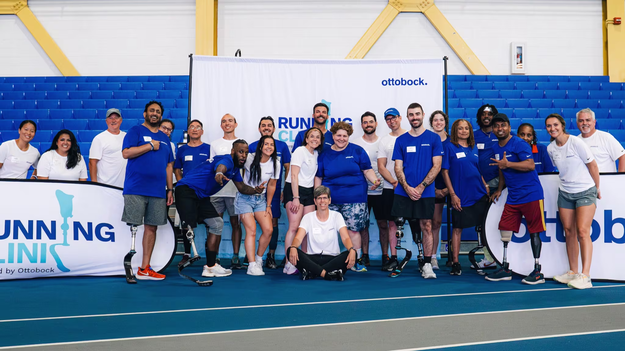 Running Clinic participants, coaches, technicians, and volunteers posing for a photo on an indoor running track
