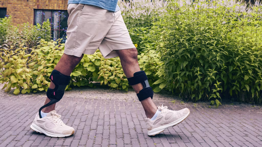 A man with orthotics walks through a garden.
