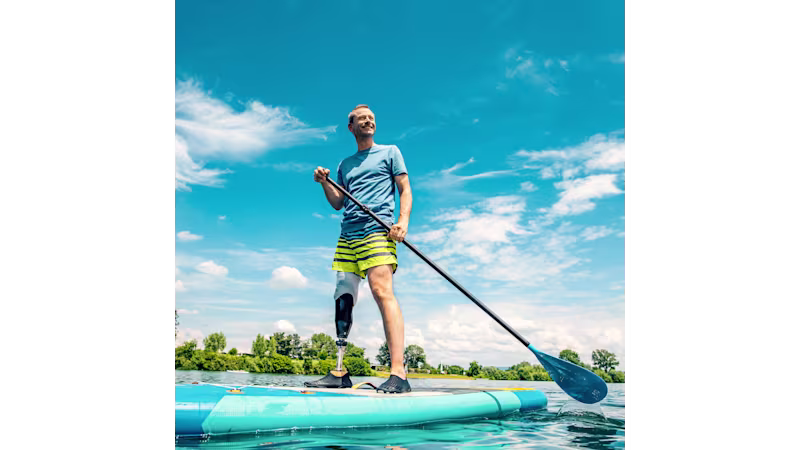 A male user is standing on his stand up paddle board with his Taleo Side Flex carbon foot.