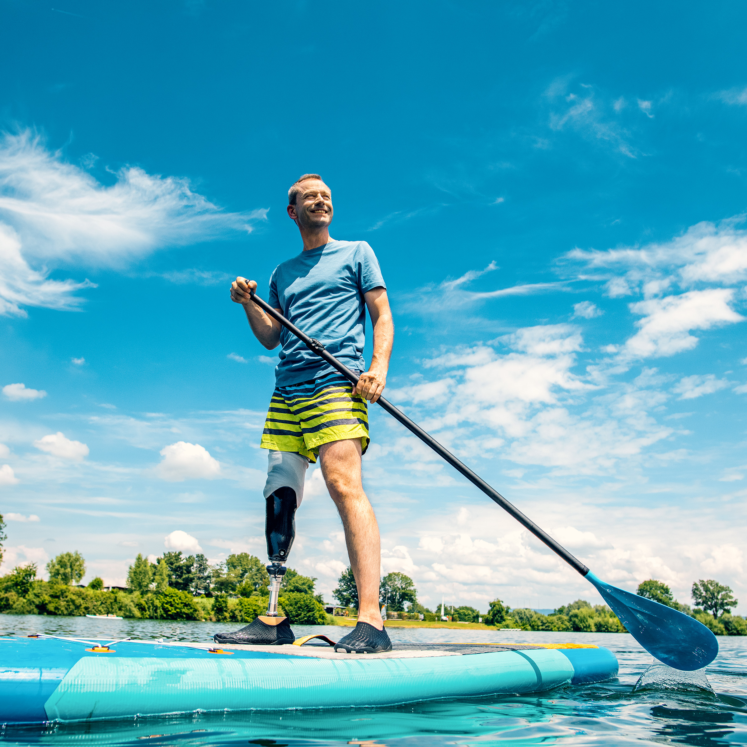 Bir erkek kullanıcı Taleo Side Flex karbon ayağıyla ayakta kürek tahtasının üzerinde duruyor.