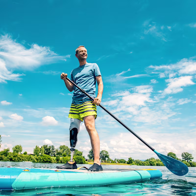 Bir erkek kullanıcı Taleo Side Flex karbon ayağıyla ayakta kürek tahtasının üzerinde duruyor.