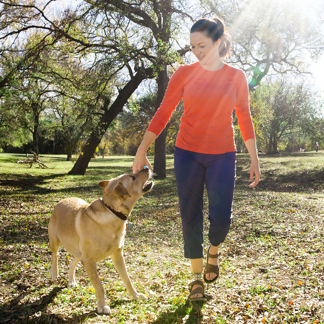 Un utilisateur de pied prothétique Taleo jouant avec son chien dans un parc