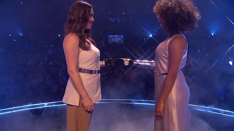 Two women with an upper limb difference fingertips touch wearing their Ottobock bebionic prosthetic hands during the Eurovision Song Contest performance of "Mountain".