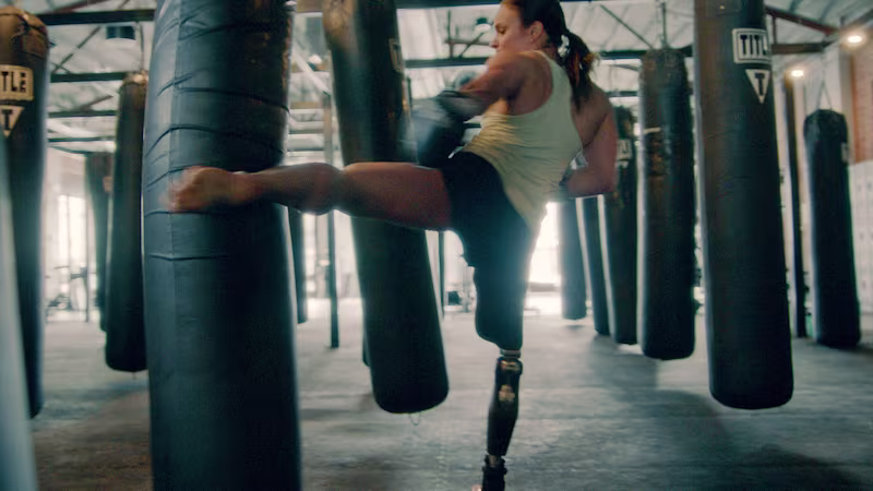 Amy stands on her C-Leg 4 as she kicks a heavy bag with her other leg
