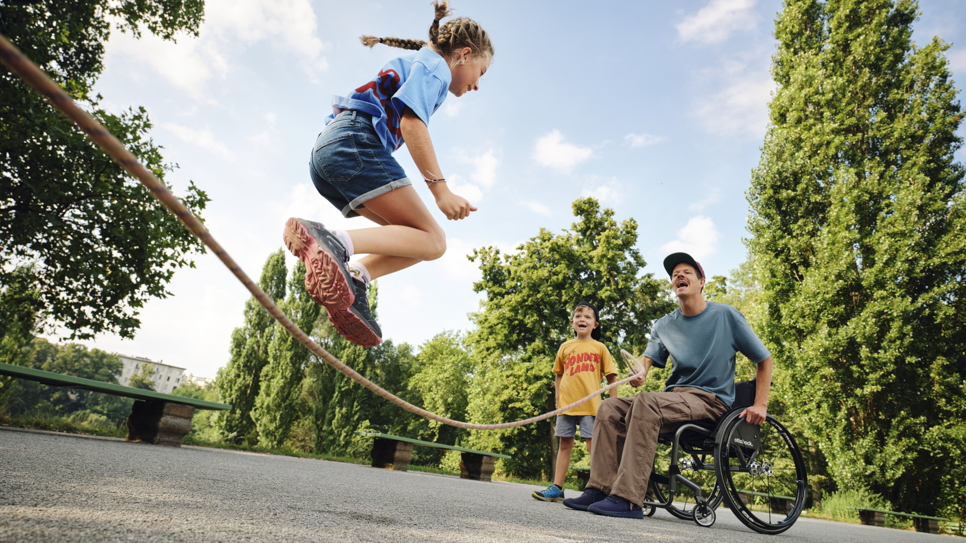 exopulse suit user Ricky in wheelchair holds rope for jumping child.