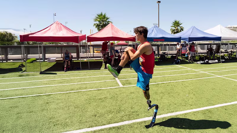 Ezra, usuario de la pala para correr, estirando en un campo al aire libre para prepararse para un día activo