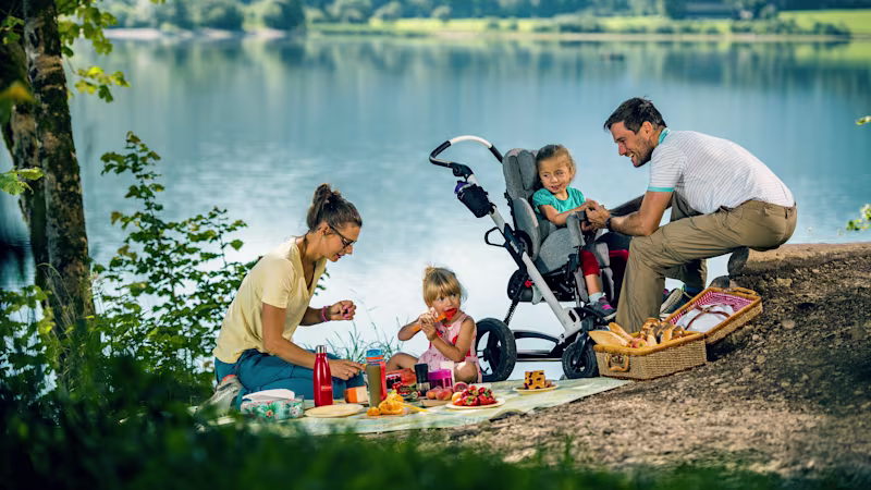 Emilia macht ein Picknick mit ihrer Familie und sitzt im Kimba Reha-Kinderwagen