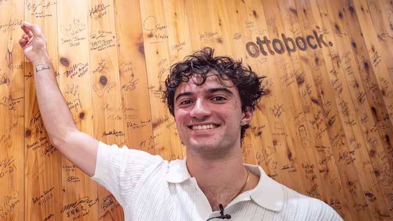 Ottobock Ambassador Ezra Frech pointing at his signature on the iconic wood wall in the Ottobock Austin headquarters