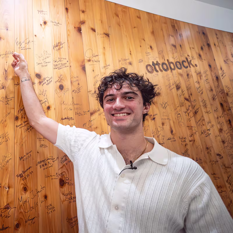 Ottobock Ambassador Ezra Frech pointing at his signature on the iconic wood wall in the Ottobock Austin headquarters