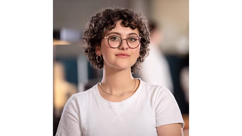 Ritratto di Lina in camicia bianca e collana, viso sfocato per la privacy.