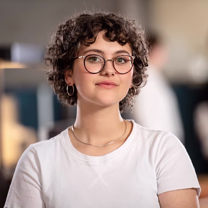 Ritratto di Lina in camicia bianca e collana, viso sfocato per la privacy.