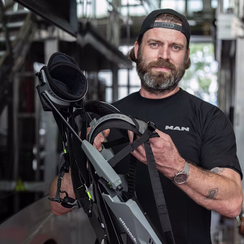 Auf dem Bild sieht man einen Mann der ein Ottobock Exoskelett in der Hand hält.