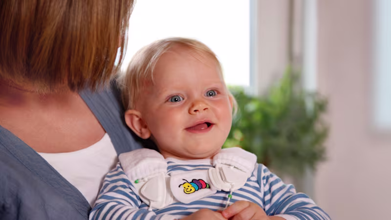 Ein kleines Kind lächelt, während es von einer Frau gehalten wird